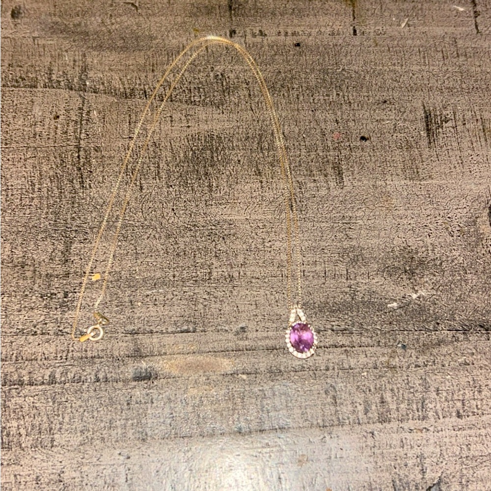 Necklace with a purple gemstone and diamonds around it.